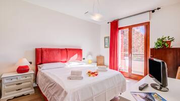 Una camera d'albergo con un letto, un comodino, una lampada e una scrivania con un computer.