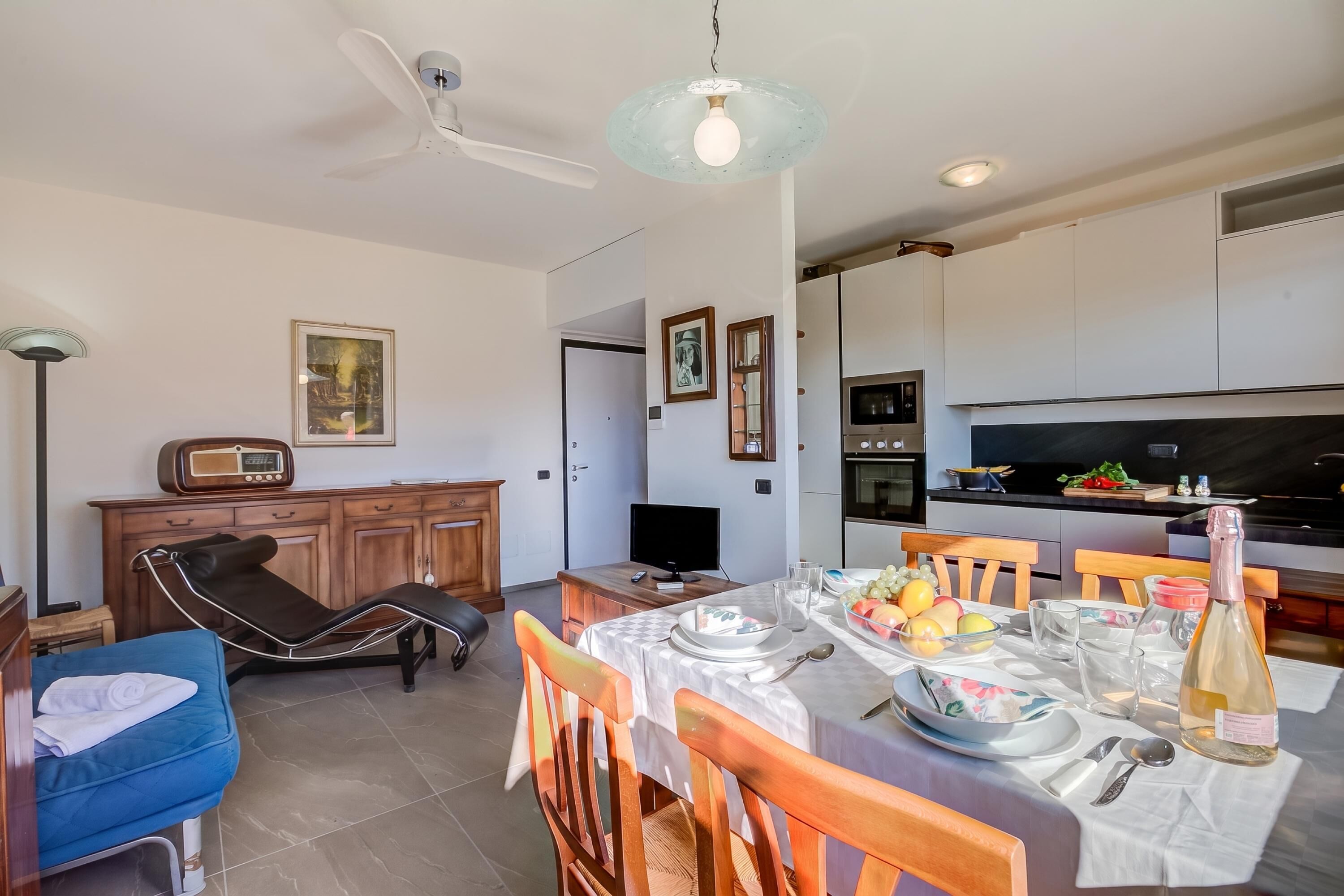A modern kitchen with a dining area, a ceiling fan, and a table set for a meal.