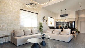Ein modernes Wohnzimmer mit einer Eckcouch, einem runden Couchtisch und einer Küchenzeile im Hintergrund.