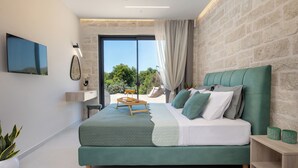 Ein modernes Schlafzimmer mit einem großen Bett, einem Deckenventilator, einem Fernseher und Blick auf Grünflächen.