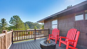 A deck with a fire pit, two red Adirondack chairs, and a view of a forested hillside. - Mtn-view Retreat w/ Deck & Hot Tub in Estes Park! (Estes Park)
