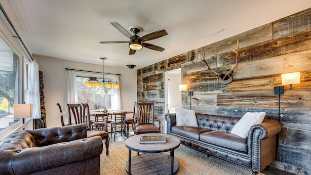 A modern living room with a fireplace, leather sofas, a round coffee table, and a rustic wooden wall. - Mtn-view Retreat w/ Deck & Hot Tub in Estes Park! (Estes Park)