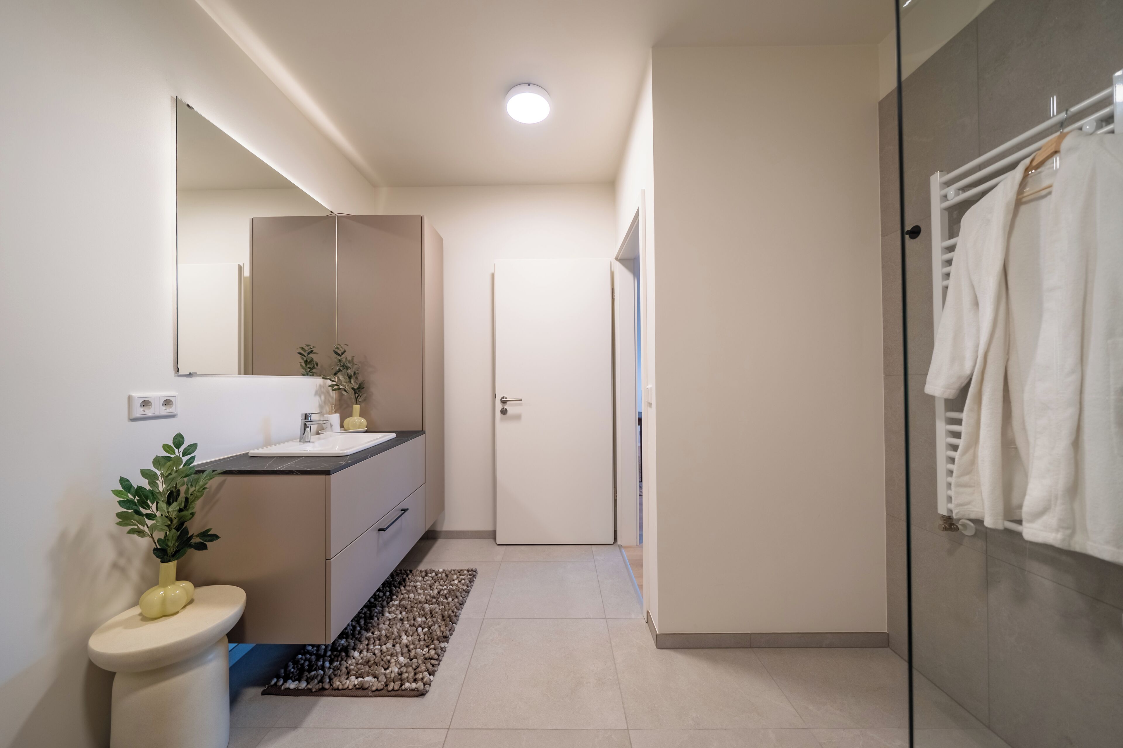 Un baño moderno con inodoro, lavabo, espejo y zona de ducha.