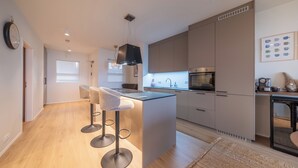 A modern kitchen with a central island, bar stools, and a coffee machine. - Ice Apartments (Reykjavík)