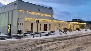 A modern building with a flat roof, large windows, and a sign indicating a pedestrian crossing. - Ice Apartments (Reykjavík)