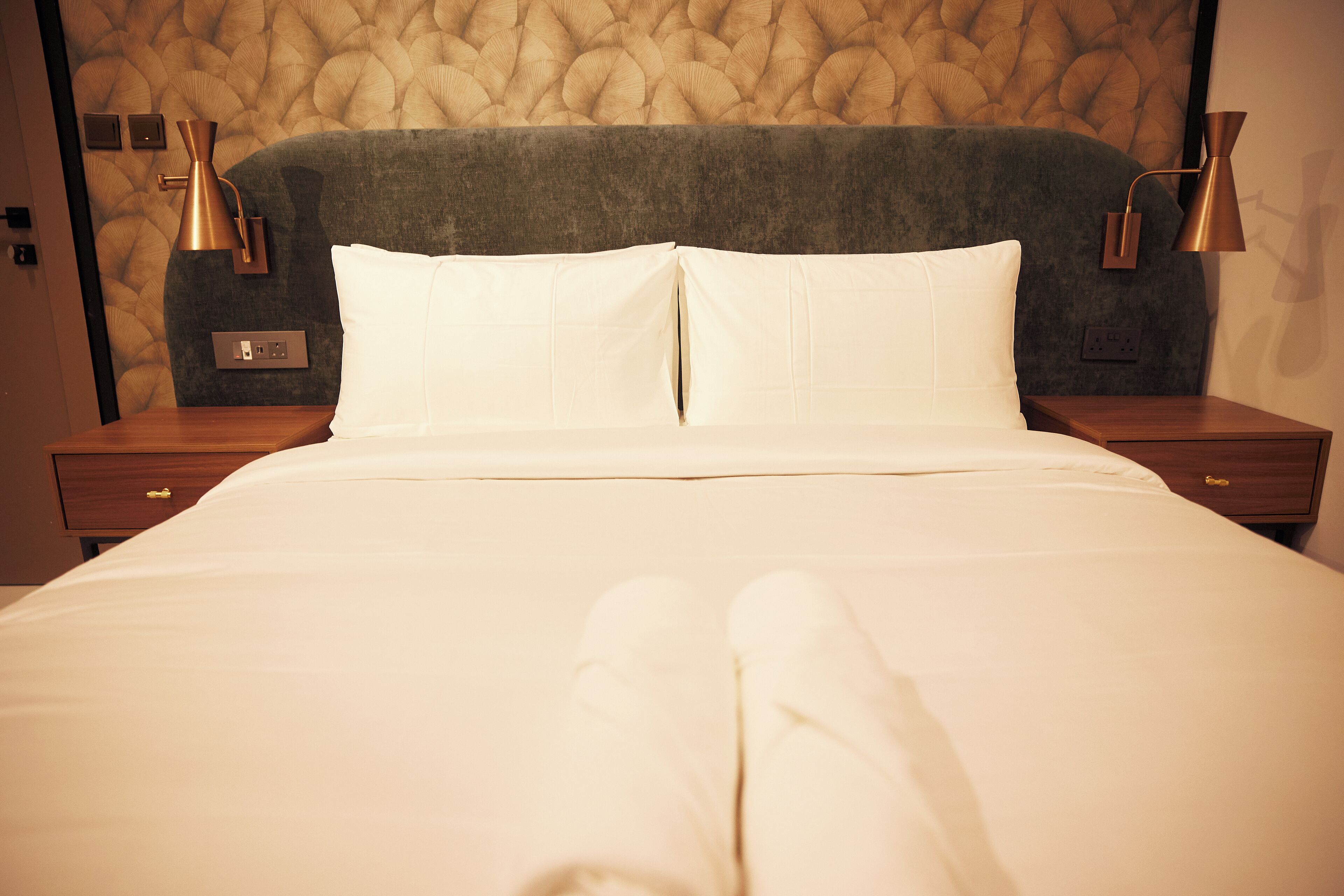 A neatly made bed with white linens, a tufted headboard, and two bedside lamps.
