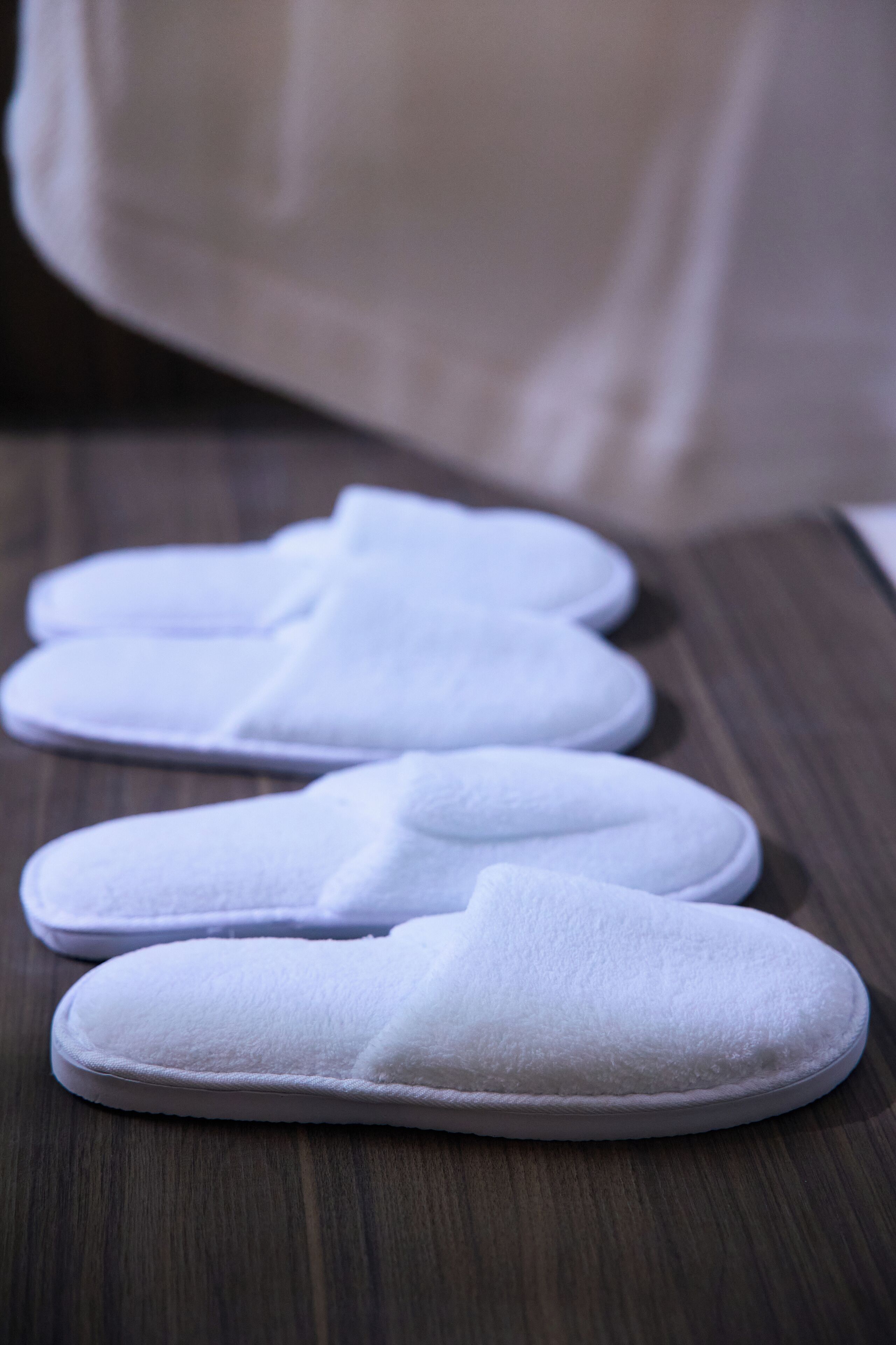 A pair of white slippers on a wooden floor.