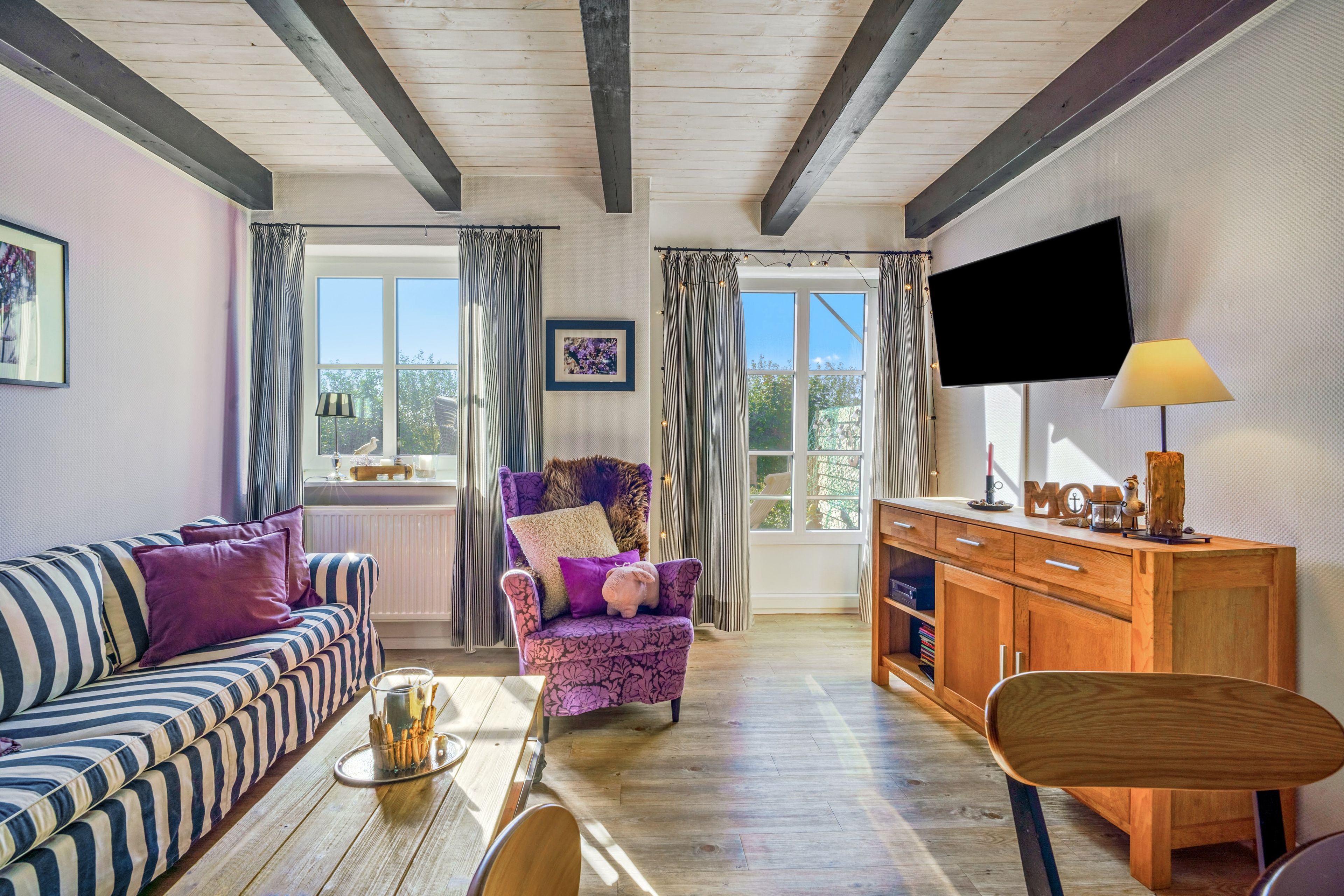 A cozy living room with a sofa, armchair, wooden cabinet, and a television.
