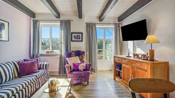 A cozy living room with a sofa, armchair, wooden cabinet, and a television.