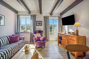 A cozy living room with a sofa, armchair, wooden cabinet, and a television. - Apartment 'Inselliebe' with Private Terrace, Shared Garden & Wi-Fi (Pellworm)