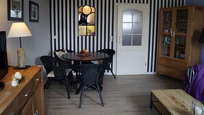 Ein Essbereich mit einem runden Tisch, schwarzen Stühlen, einer Holzkabine und einem Fernseher auf einer Holzkommode.
