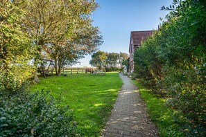 Een geplaveid pad dat door een gazon met bomen en een gebouw op de achtergrond loopt.