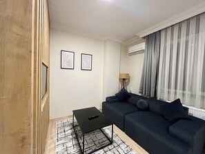 Un salon moderne avec un canapé bleu foncé, une petite table basse noire et deux œuvres d’art abstraites accrochées au mur.