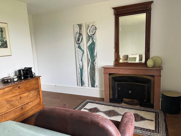 A room with a fireplace, a wooden dresser, a sofa, and abstract wall art. - Domaine les Darbonnets (Chavannes-sur-Reyssouze)