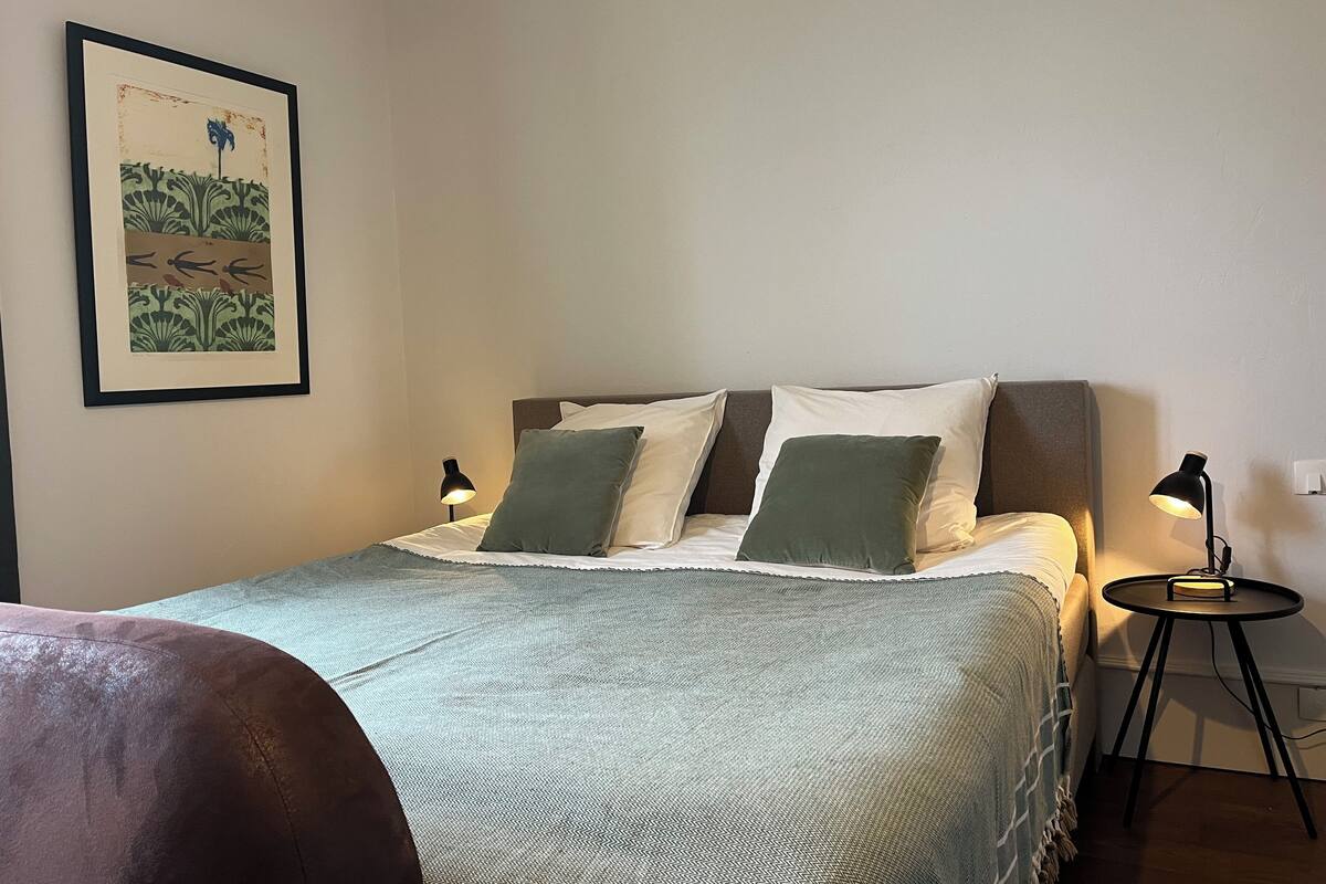 A neatly made bed with a patterned bedspread, two pillows, and a bedside lamp.