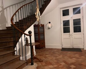 A wooden staircase with a lantern on the landing, a white door with glass panels, and a patterned floor. - Domaine les Darbonnets (Chavannes-sur-Reyssouze)
