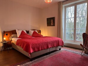 A bedroom with a bed, a nightstand, a chair, and a window with a view of trees. - Domaine les Darbonnets (Chavannes-sur-Reyssouze)