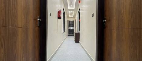A long, narrow hallway with wooden doors on either side and a tiled floor.