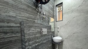 A modern bathroom with a marble wall, a white sink, and a shower. - Hotel Kalindi kunj (Mathura)