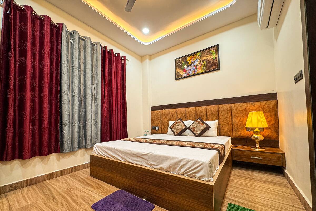 A neatly arranged bedroom with a wooden bed, a nightstand with a lamp, and a painting on the wall.
