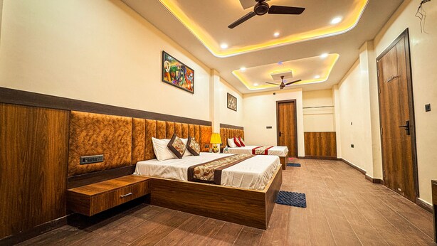 A hotel room with a large bed, a bedside table, a wardrobe, and a ceiling fan. - Hotel Kalindi kunj (Mathura)