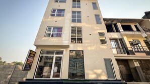 A multi-story building with a modern facade, large windows, and a prominent entrance with glass doors. - Hotel Kalindi kunj (Mathura)