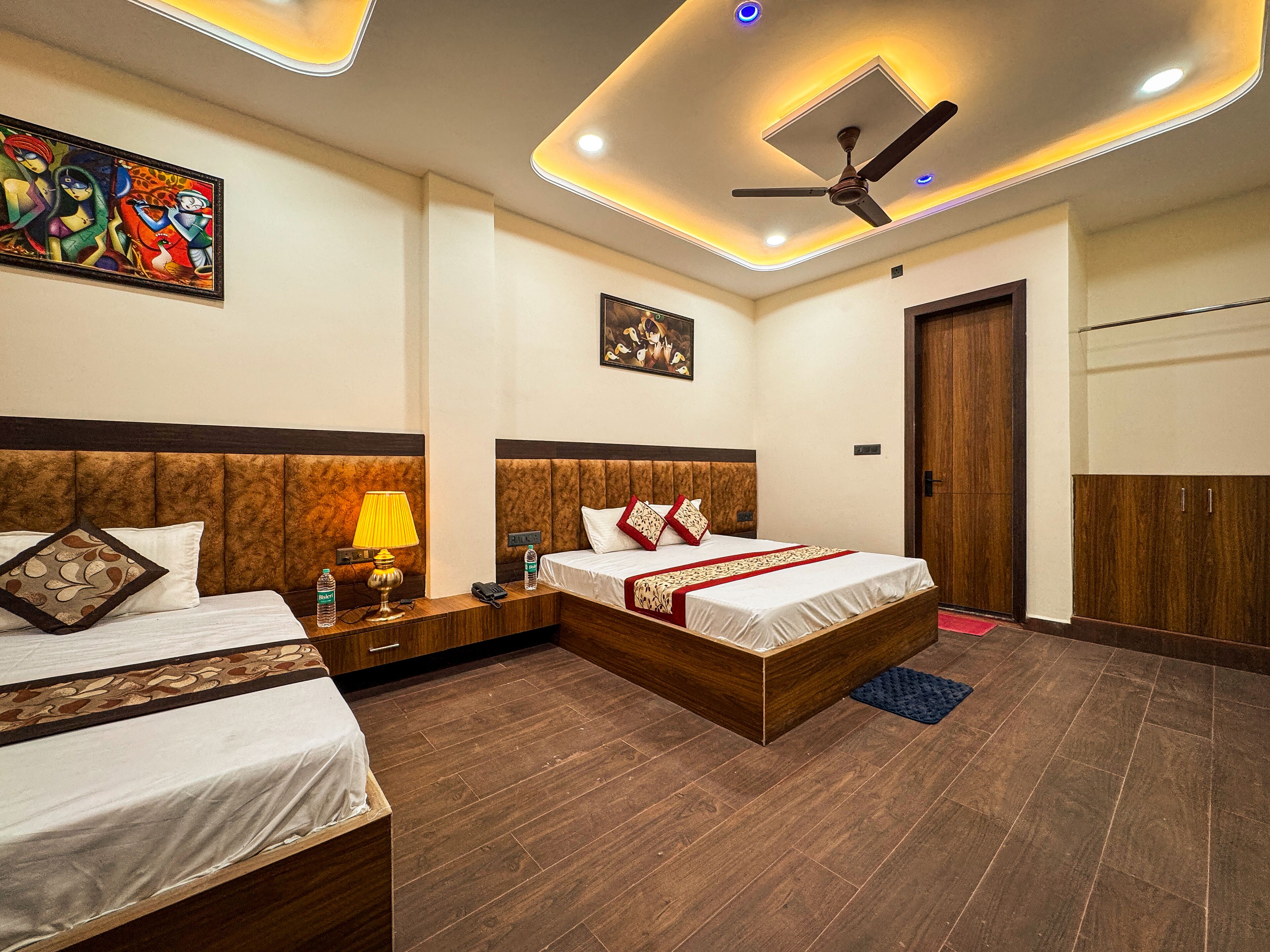 A hotel room with two beds, a ceiling fan, recessed lighting, and artwork on the walls.