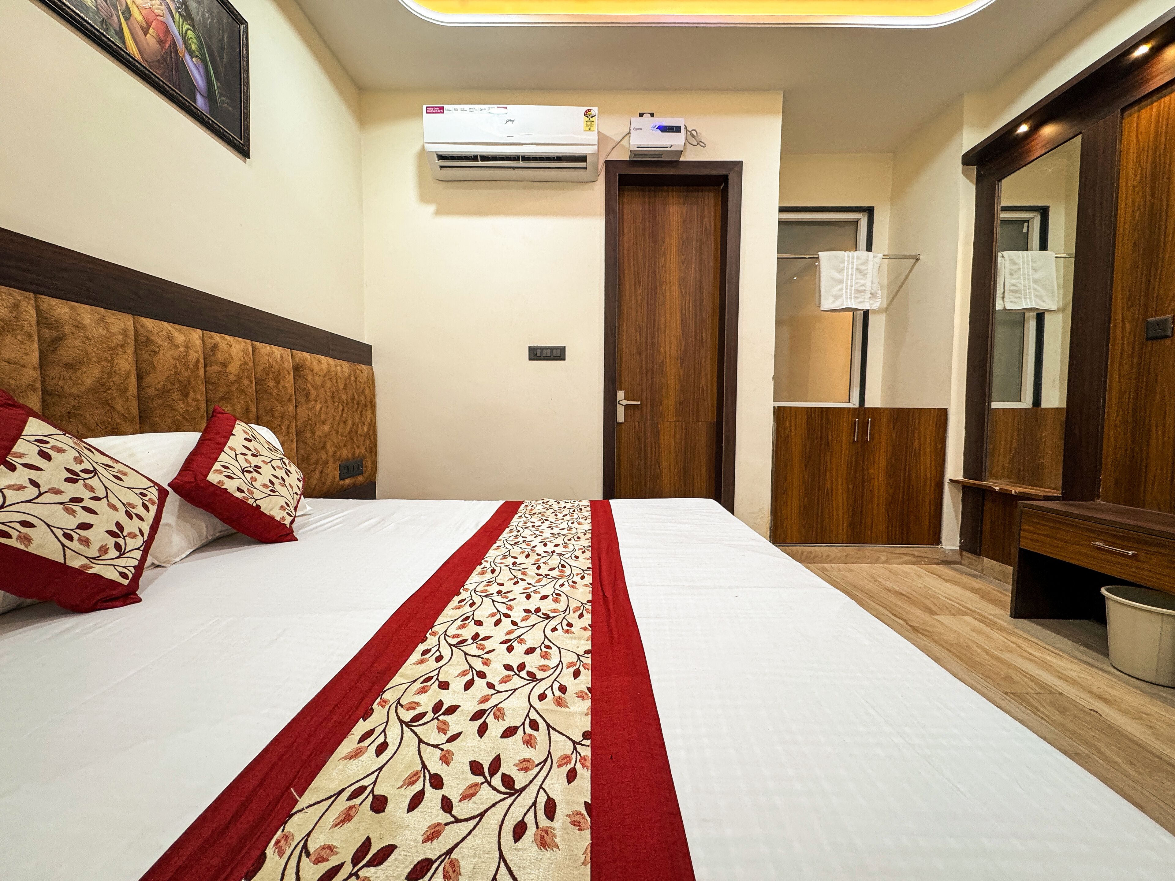 Habitación de hotel con una cama grande, un armario, un espejo y un equipo de aire acondicionado.