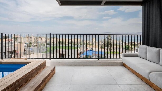 A balcony with a pool, a sofa, and a view of a cityscape. - Artemis (Tiberias)