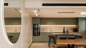 A modern kitchen with a central island, bar stools, and a dining table with benches. - Artemis (Tiberias)