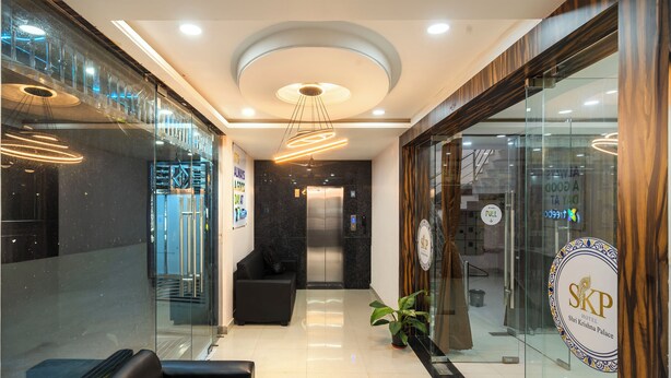 A hotel reception area with a modern design, including a reception desk, seating area, and a glass wall with a logo. - Treebo Sri Krishna Palace (Bhubaneshwar)