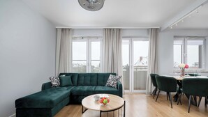Una sala de estar moderna con un sofá seccional verde, una mesa redonda de madera y un comedor con sillas verdes.