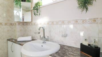 A bathroom with a white sink, a mirror, a towel, and decorative plants.