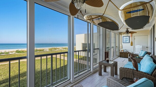 A balcony with a view of the beach, wicker furniture, and ceiling fans. - Gulf-Front Escape- 2BR Beachfront Condo by RVA (Longboat Key)