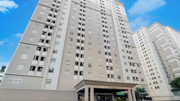 A high-rise building with multiple floors, featuring a prominent entrance labeled "HERBAS." - Hotel O Kalibata City Residence (Jakarta)