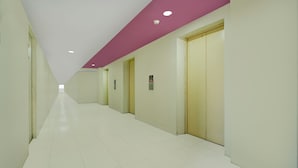 A long, narrow hallway with white tiled floors and cream-colored walls. There are doors on the right side, and the ceiling is white with a purple accent. - Hotel O Kalibata City Residence (Jakarta)