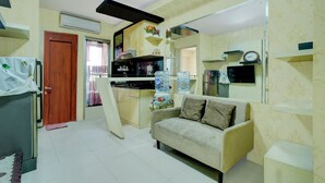 A compact living space with a kitchenette, a sofa, and a water dispenser. - Hotel O Kalibata City Residence (Jakarta)