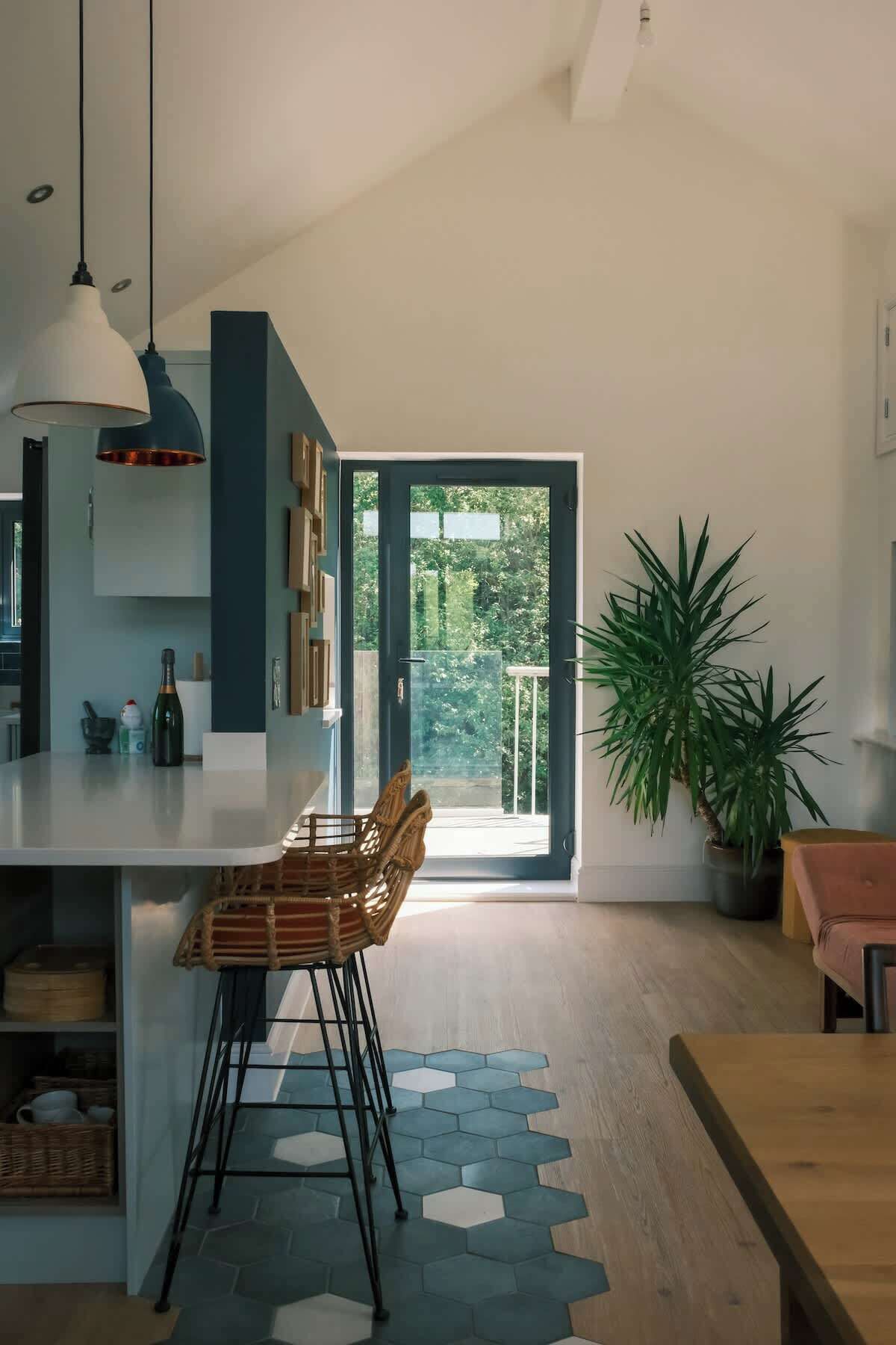 A modern kitchen with a large island, pendant lighting, and a view of the outdoors.