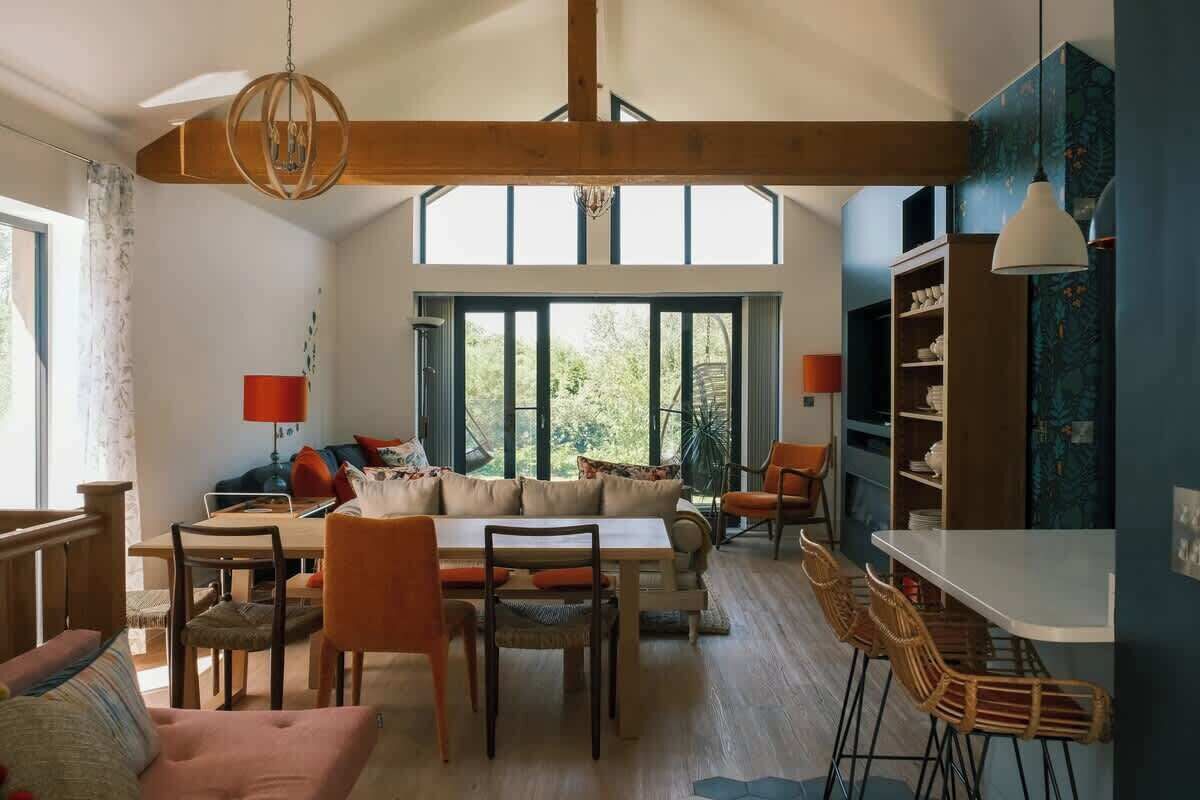 Un vaste espace de vie doté d’un haut plafond, de grandes fenêtres, d’une table à manger et d’un coin cuisine.