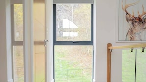 A spacious room with a large window, wooden flooring, and a framed artwork on the wall.