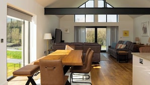 A spacious living area with a large dining table, comfortable seating, and a view of the outdoors.