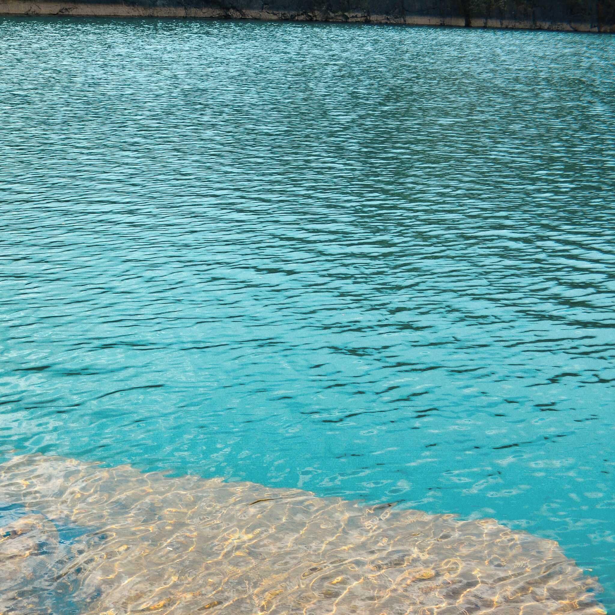 Vista chiara di una piscina con bordo roccioso e una sporgenza in pietra in primo piano.