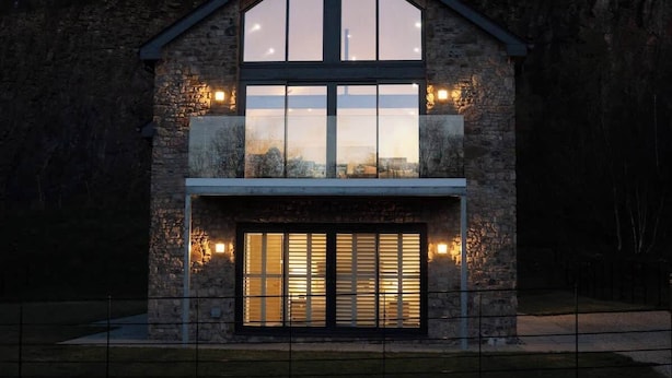 A modern stone house with large windows and a garage.