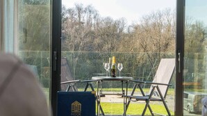 A glass-enclosed balcony with a table, two wine glasses, and a bottle of wine.