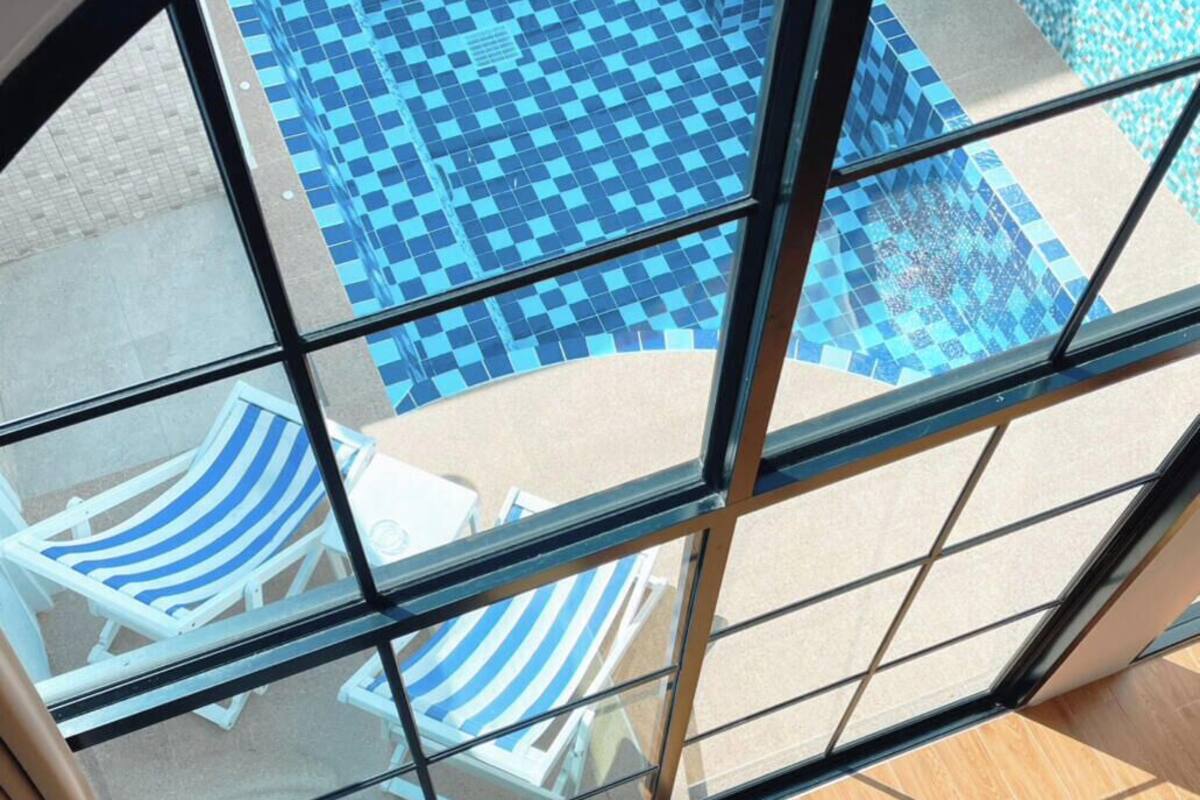 Una habitación con vista a un área de piscina, que incluye sillas de descanso a rayas y piso de piscina a cuadros.