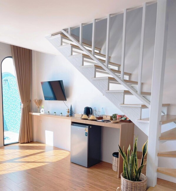 A modern kitchen with a built-in dishwasher, a wooden countertop, and a staircase with white railings. - Alan Pool Villa Bangsaen (Chonburi)