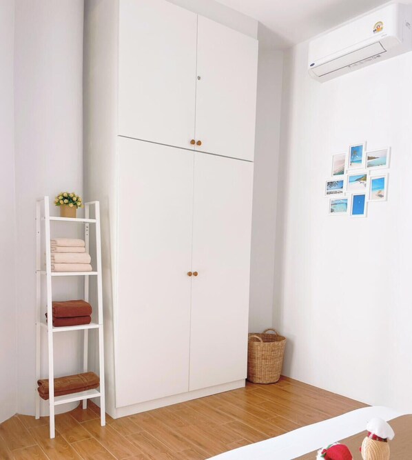 Una habitación con un armario blanco, un estante con toallas dobladas y una pared con fotografías.