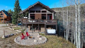 A two-story house with a balcony, a hot tub, and a stone fireplace surrounded by red chairs. - Ski Inn Condo 1 Bedroom Condo (Winter Park)
