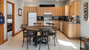A modern kitchen with wooden cabinets, a central island, and a dining area with a round table and chairs. - Ski Inn Condo 1 Bedroom Condo (Winter Park)