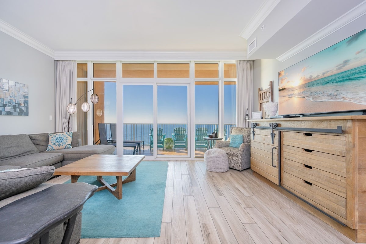 A modern living room with a large window, a sofa, a coffee table, and a TV on a wooden cabinet.